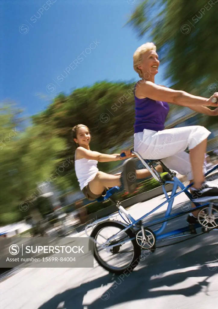 Mature woman and girl riding bikes, blurred