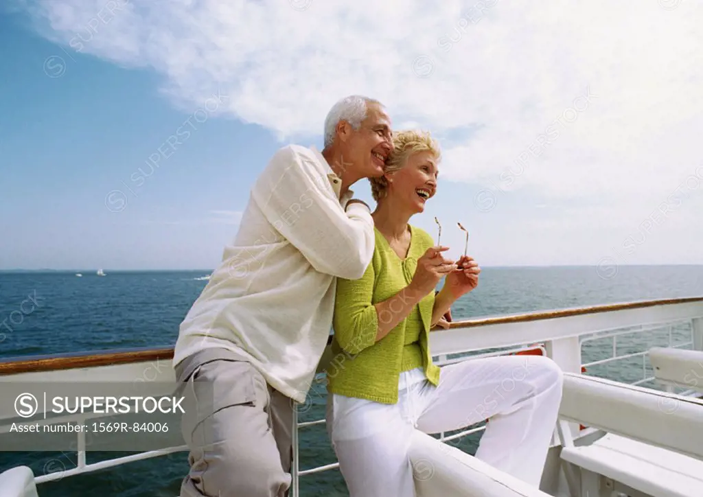 Mature couple leaning against railing, smiling