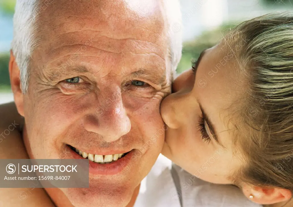 Girl kissing mature man on cheek, close-up