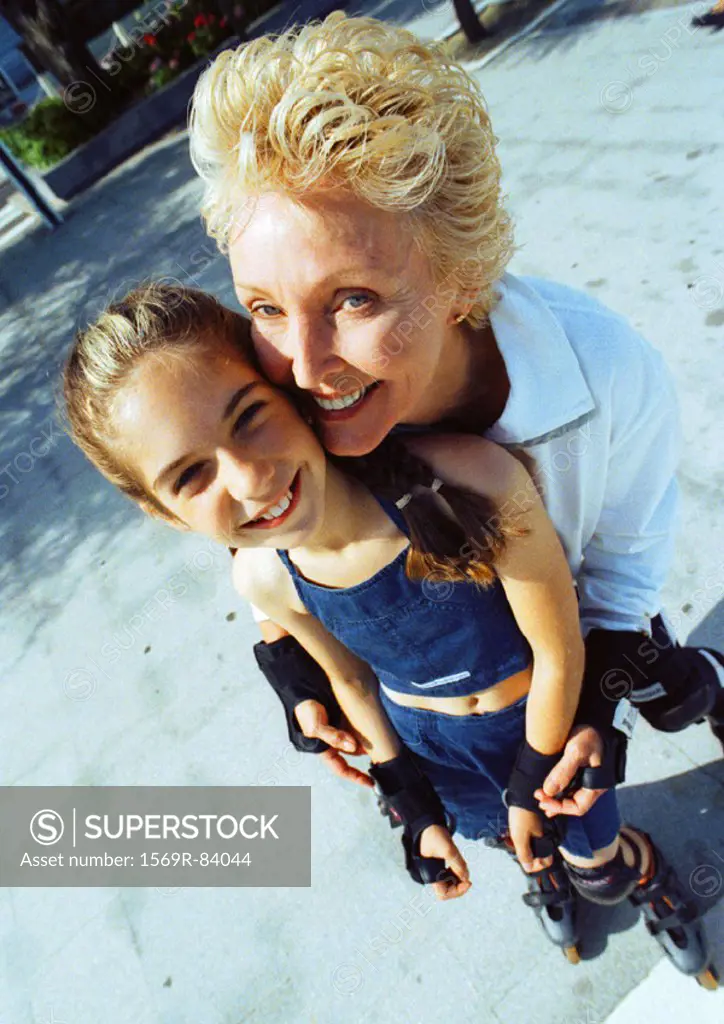 Mature woman and young girl on in line skates, smiling, high angle view