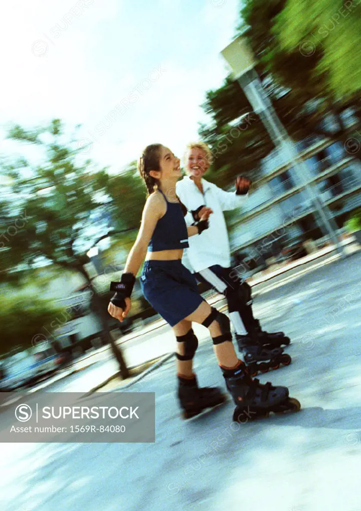 Mature woman and young girl in line skating, blurred