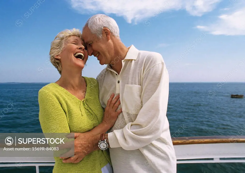 Mature couple embracing, laughing on boat deck