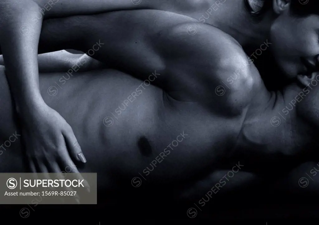 Woman touching nude man´s abdomen from behind, close-up, black and white