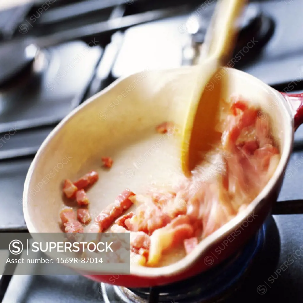 Close-up of bacon cubes being cooked in skillet