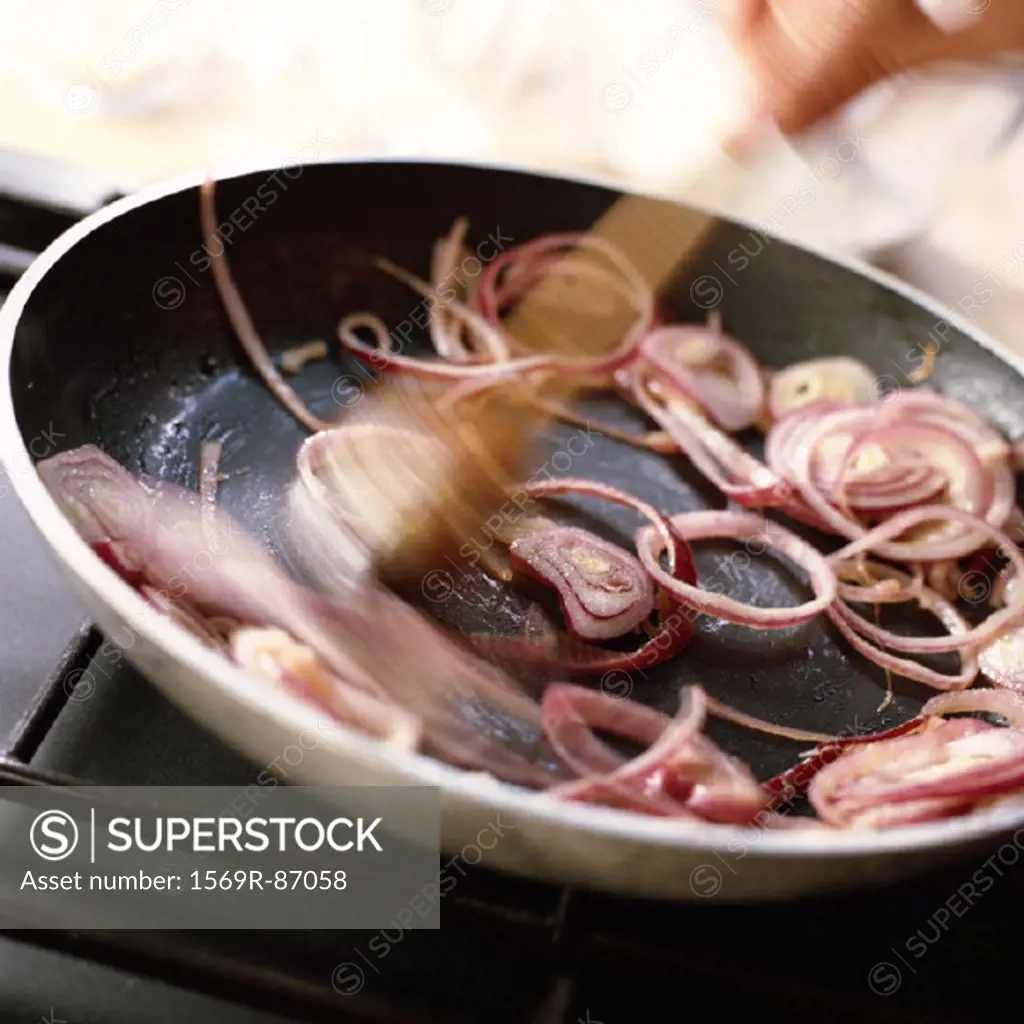 Close-up of red onions being sauted in a pan
