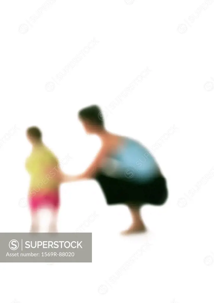 Silhouette of woman squatting down next to child, on white background, defocused