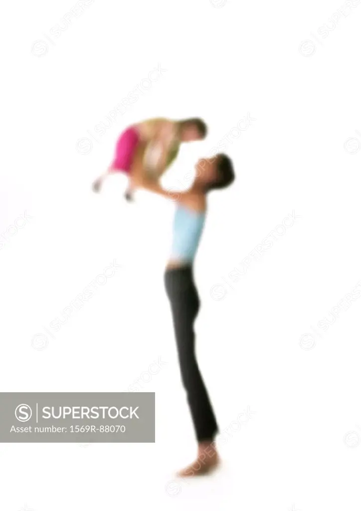 Silhouette of woman holding up child in air, on white background, defocused