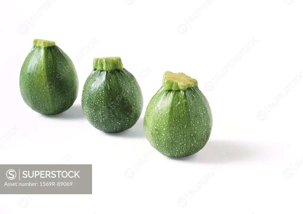 Three globe zucchini, standing on ends, in diagonal line