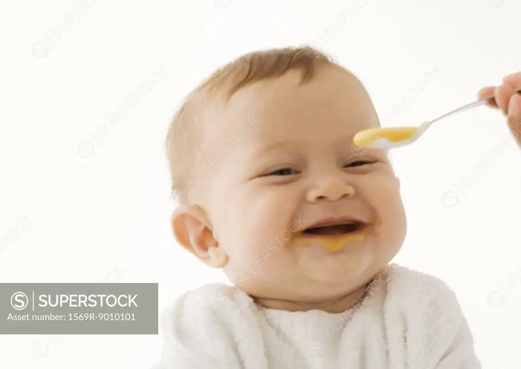 Smiling baby being fed baby food