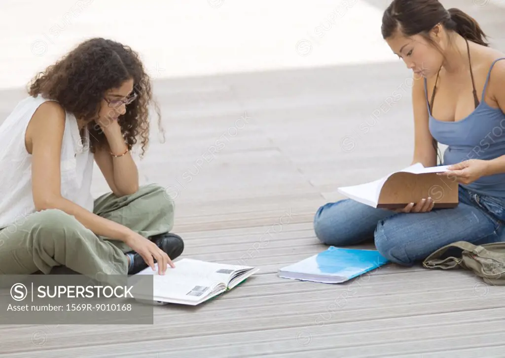 Two students sitting on ground, studying