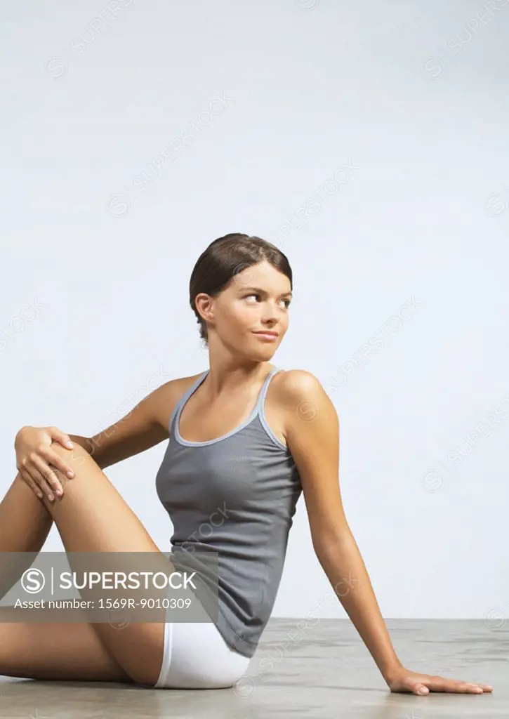 Young woman sitting on floor doing stretches