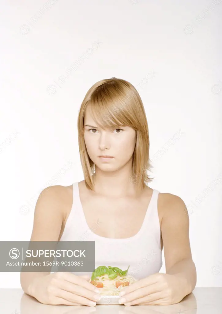 Young woman with arms around plate of pasta