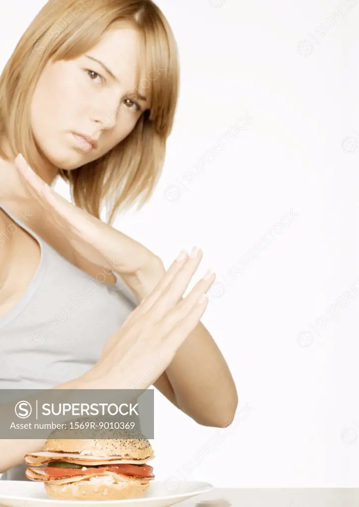 Young woman crossing arms, looking at sandwich