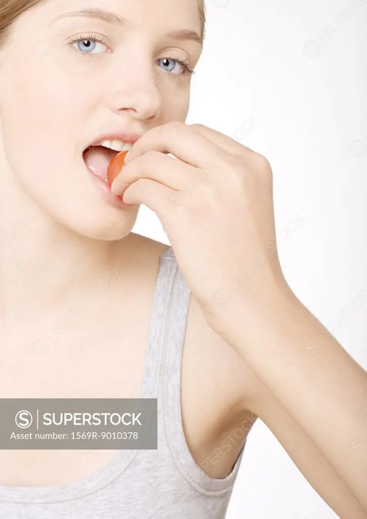 Young woman biting into tomato