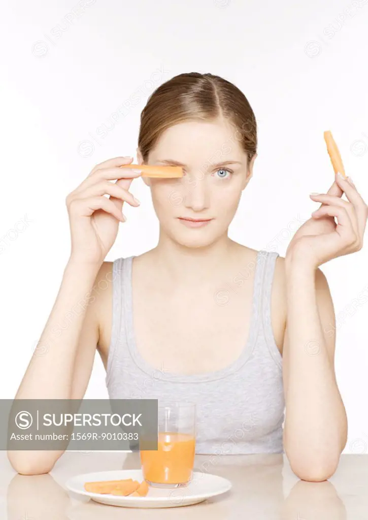 Young woman with carrot sticks and carrot juice