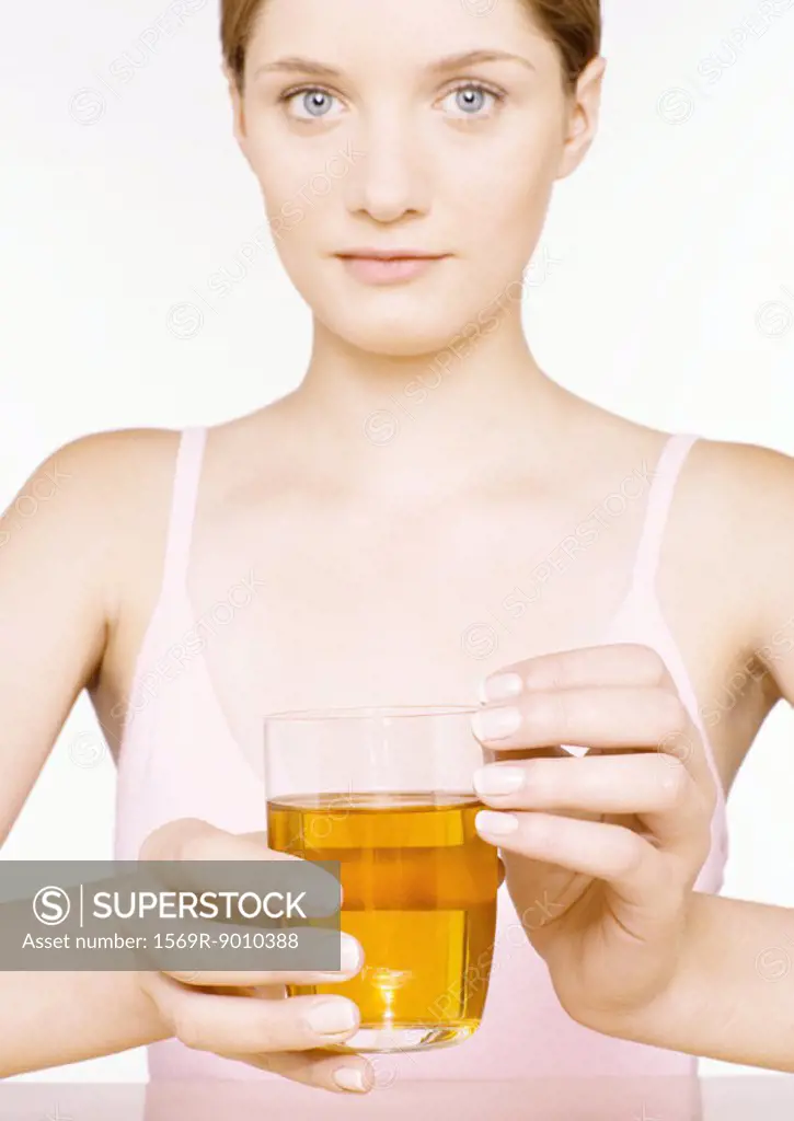 Young woman holding out glass of apple juice