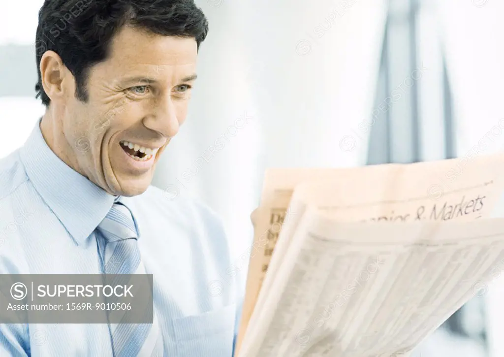 Businessman looking at newspaper excitedly