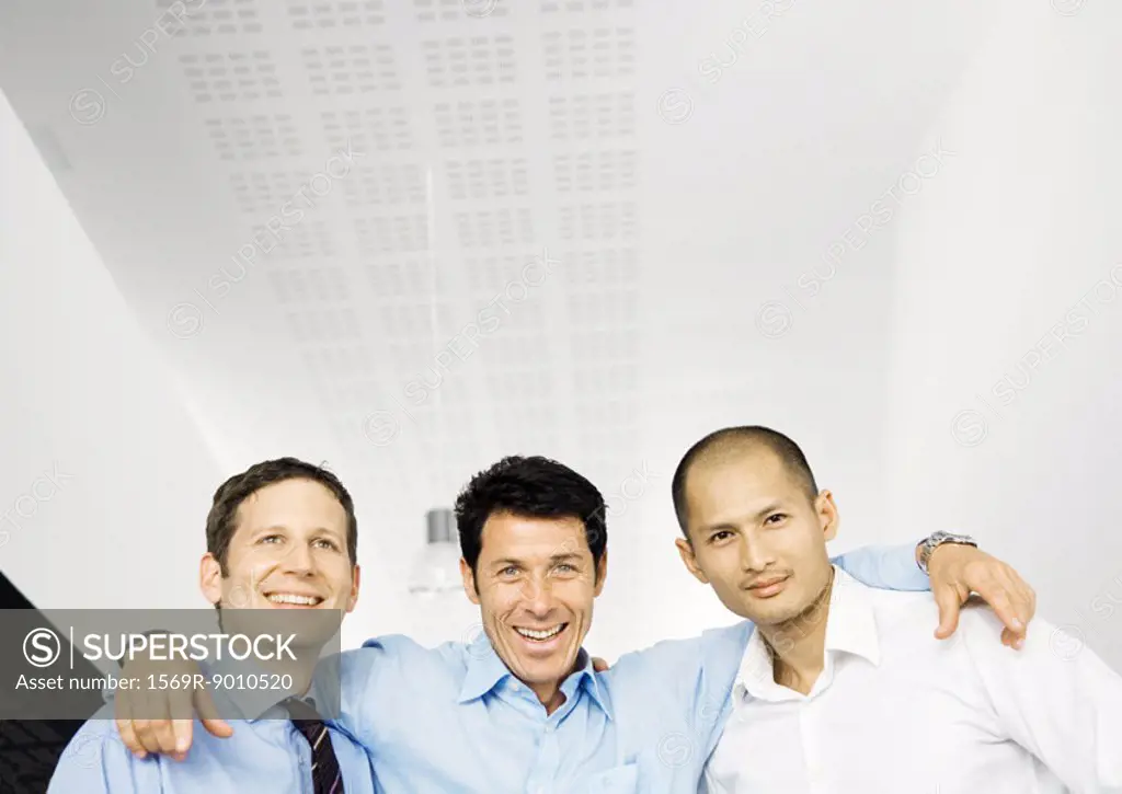Businessman standing with arms around two colleagues shoulders