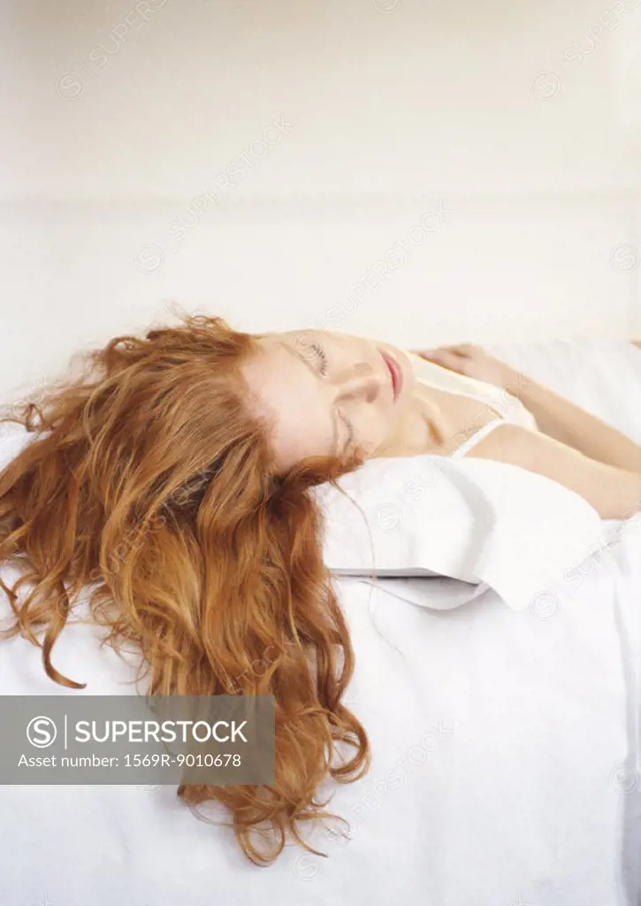 Redheaded woman lying on bed