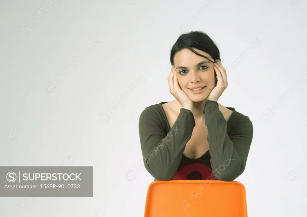 Young woman sitting backwards on chair, smiling