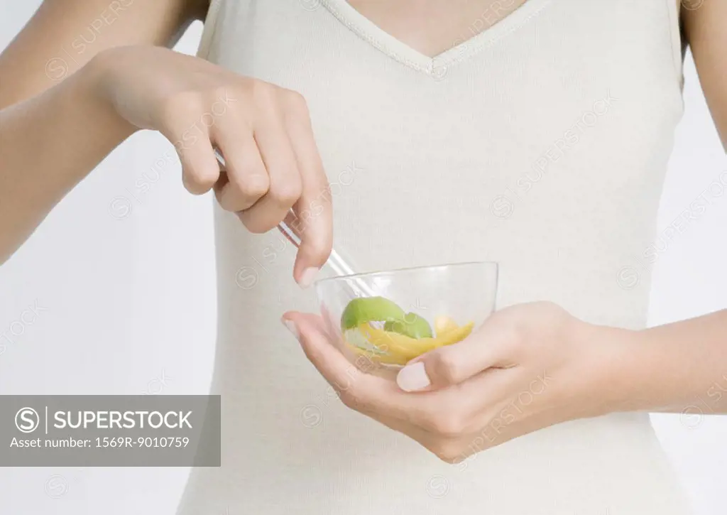 Young woman holding bowl with lemon peel and herbs