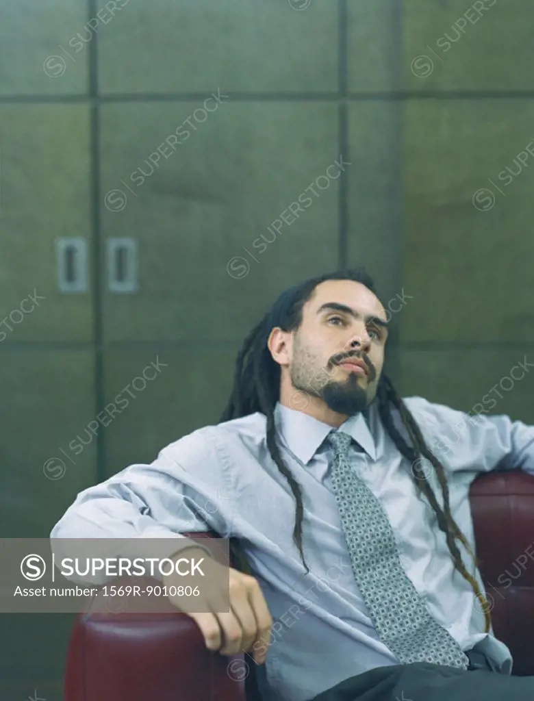 Businessman with dreadlocks leaning back, portrait