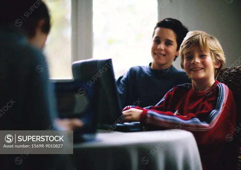 Two children using laptop and smiling