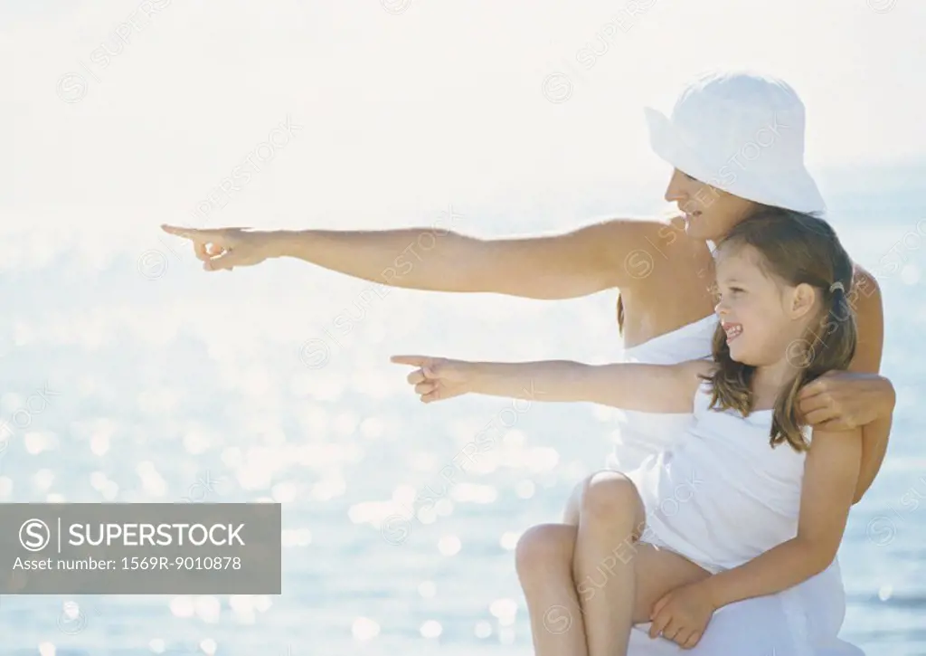 Mother and daughter pointing in front of sea
