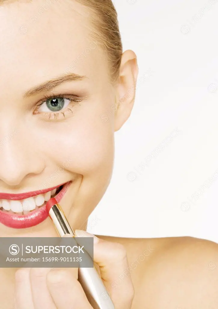 Woman applying lipstick, partial view