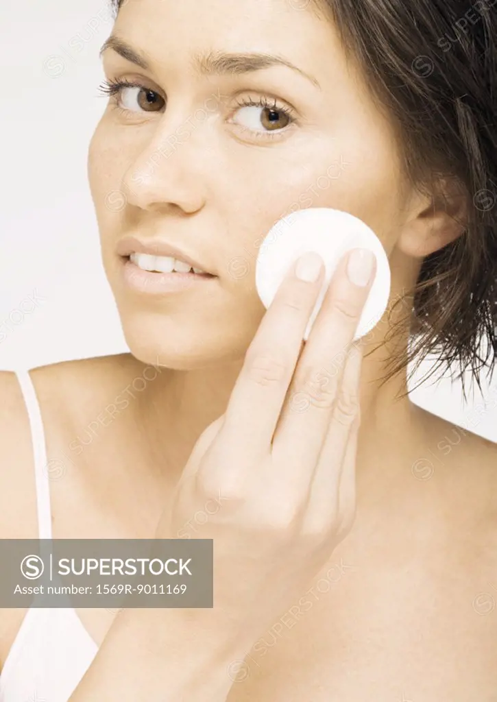 Woman using cotton pad on face