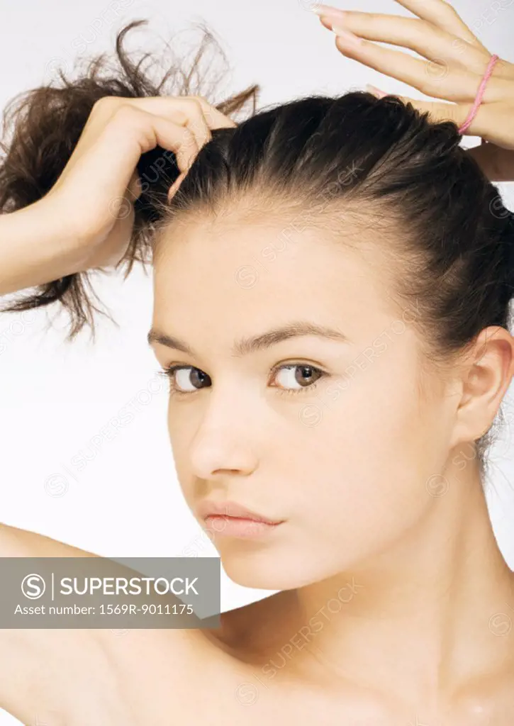 Young woman putting hair in ponytail