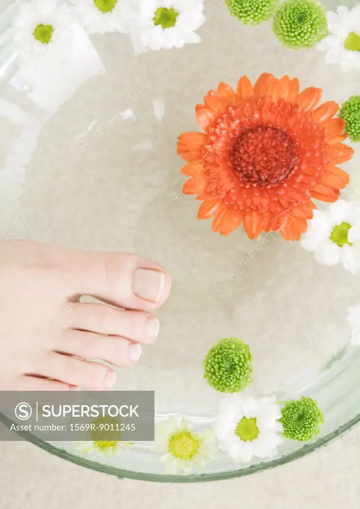 Woman´s foot and bowl of flowers floating in water