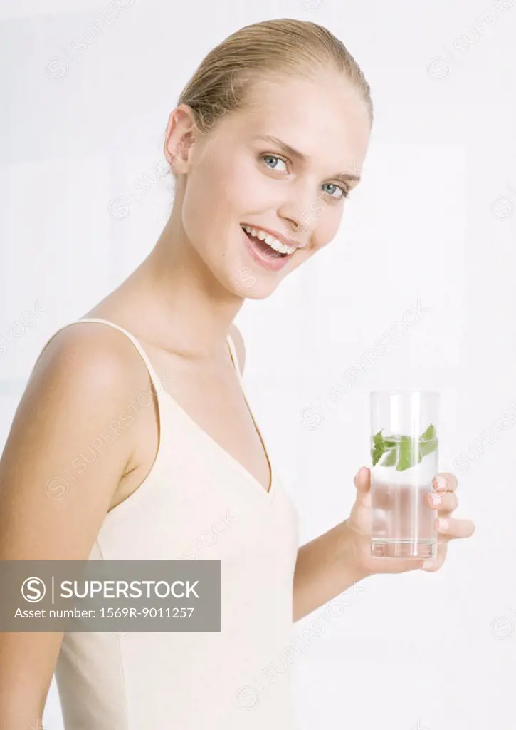 Woman smiling and holding glass of herb water