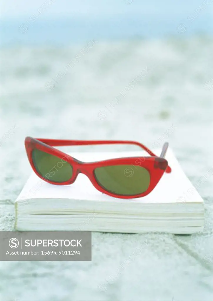 Sunglasses and book on sand
