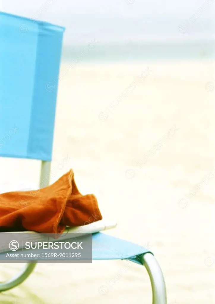 Newspaper and piece of clothing on beach chair