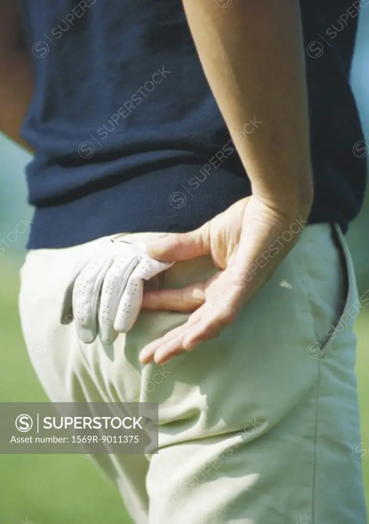 Golfer taking glove from back pocket, close-up