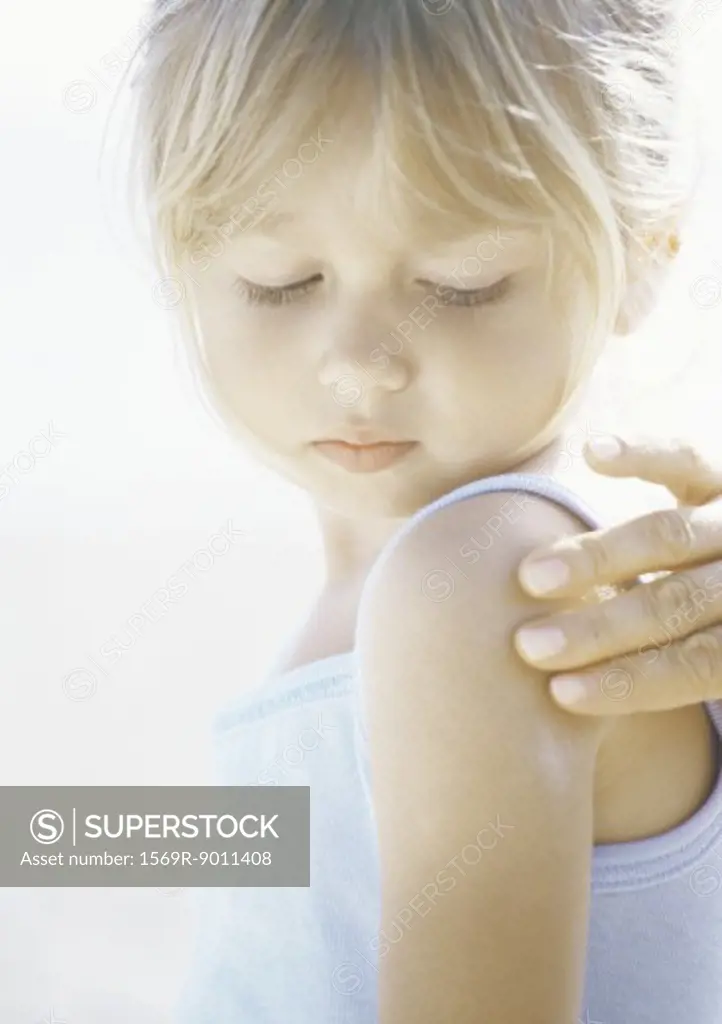 Girl having sunscreen applied to shoulder