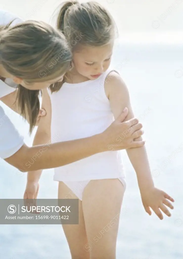 Woman looking at daughter's arm