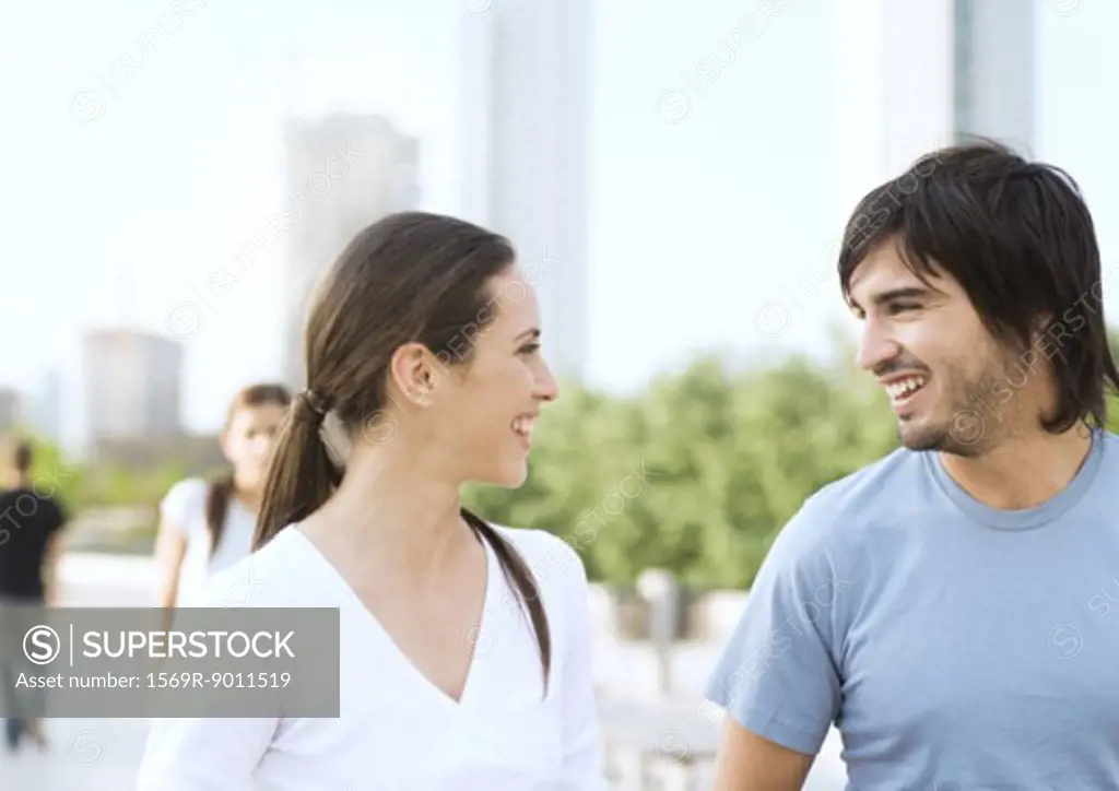Young couple smiling at each other in urban park