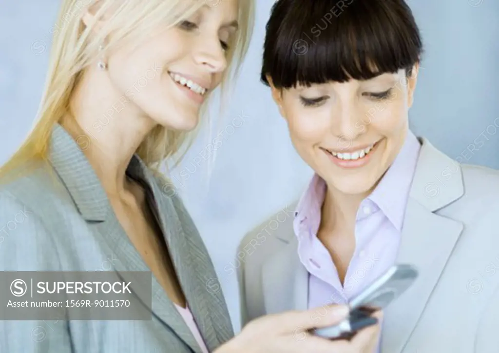 Two businesswomen looking at cell phone