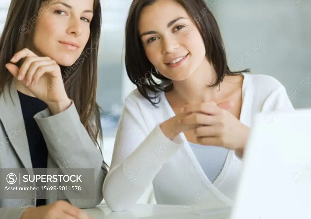 Two businesswoman sitting at desk, portrait