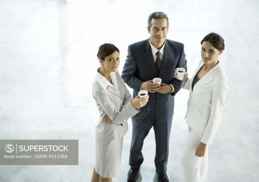 Three executives standing together with cups of coffee