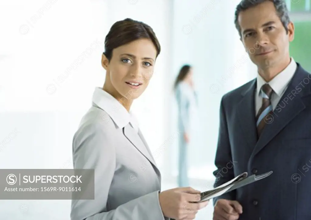Businessman and businesswoman standing with file