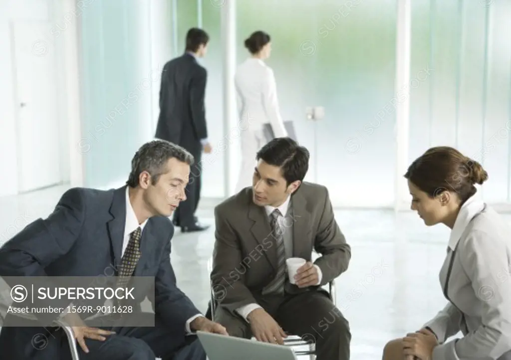Business people sitting in lobby, having discussion