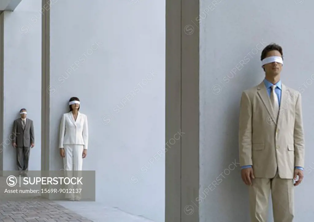 Business executives standing blindfolded