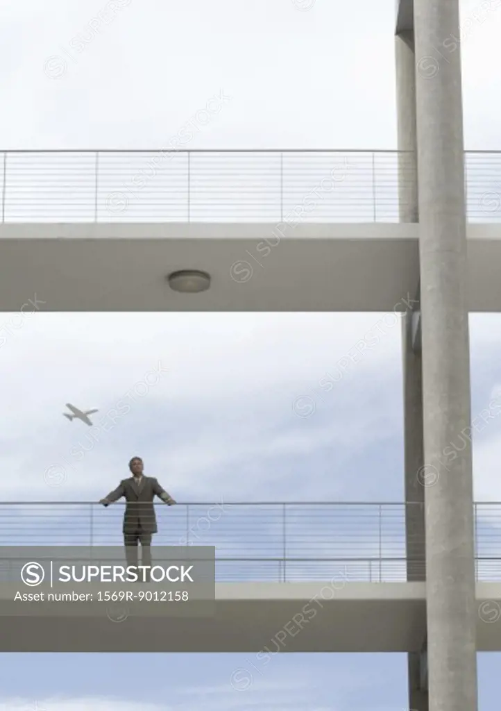 Businessman standing on walkway, plane in background