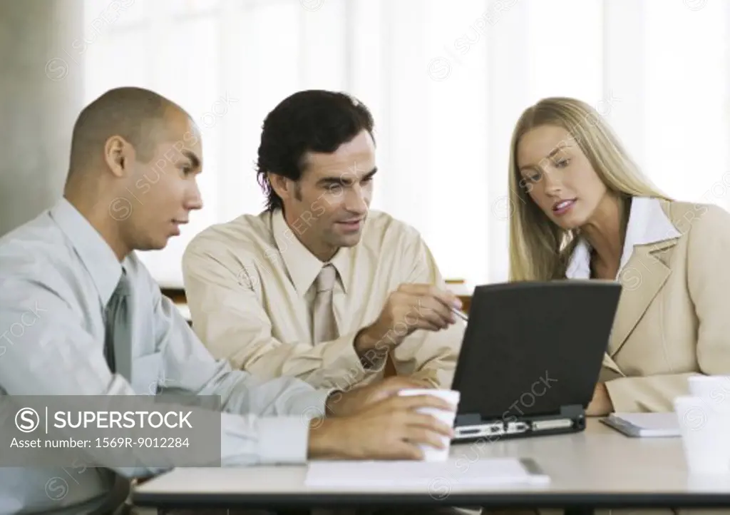 Three young executives working at laptop together