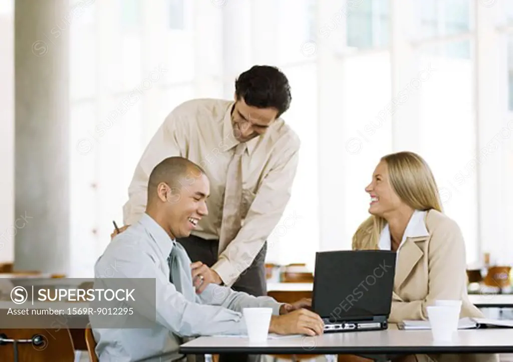 Three young executives laughing in cafeteria