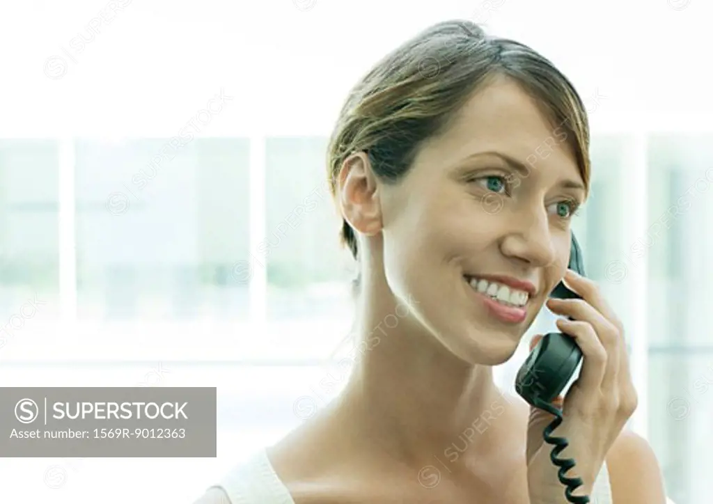 Woman using telephone, smiling