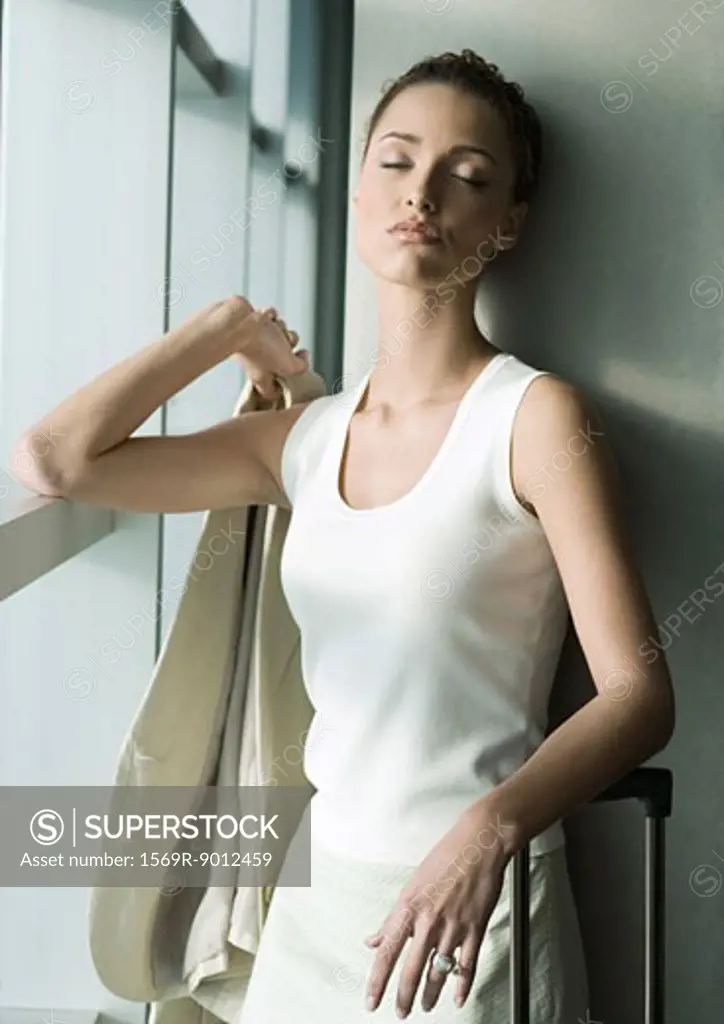 Female traveler standing by window, closing eyes 